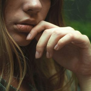 A young girl touching her mouth from pain.